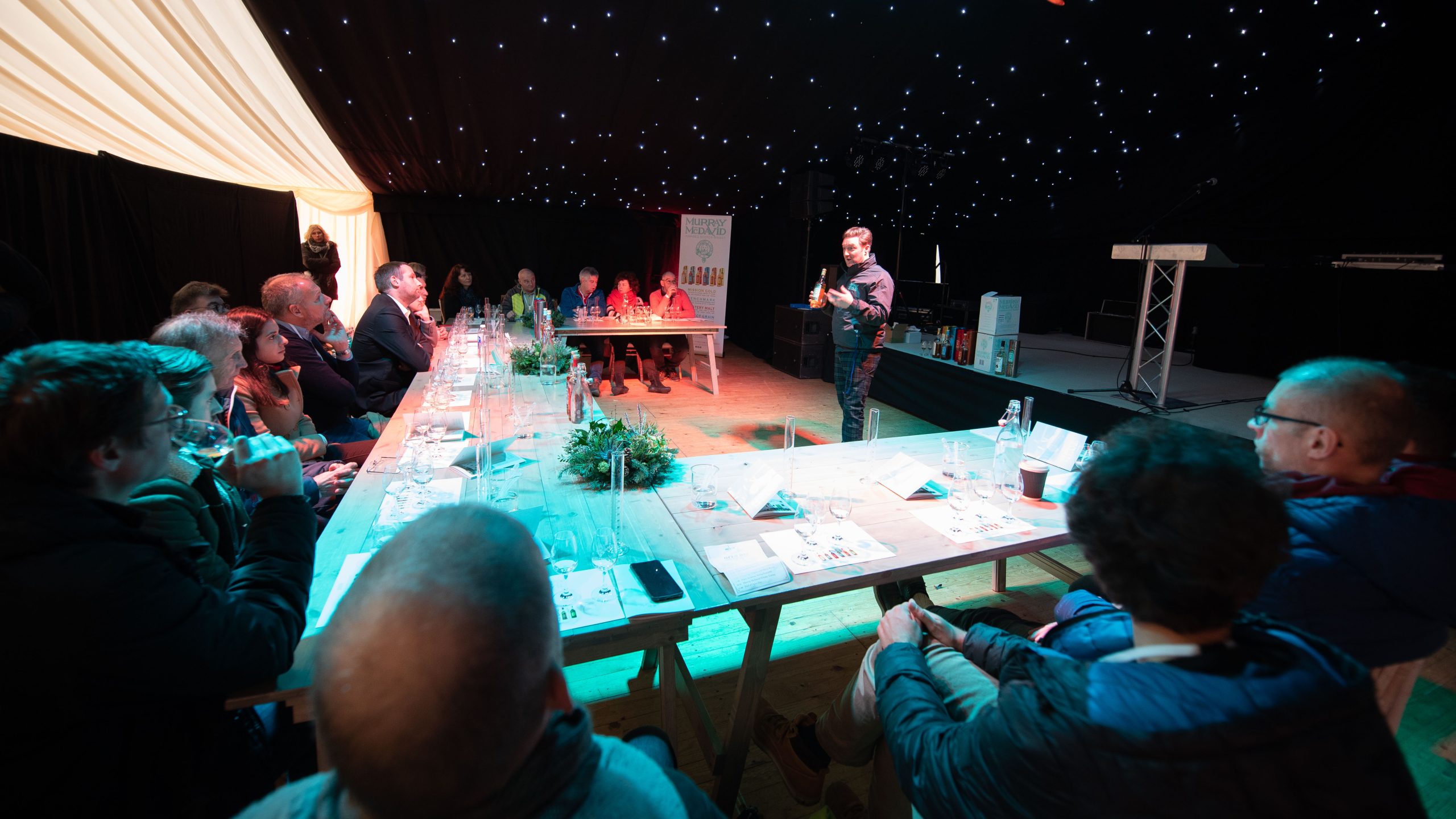 A man stood presenting in front of a table of people